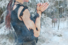 Image title: Winter wonder. A snowy winter day. A young woman walks in the forest and looks in wonder at a deer. The deer is standing still looking at the woman at a distance. The woman is wearing a black dress with lace sleeves. Her hair is brown and is in an up do except a tail hanging down her back. Rendered in Daz Studio and postwork done in photoshop.